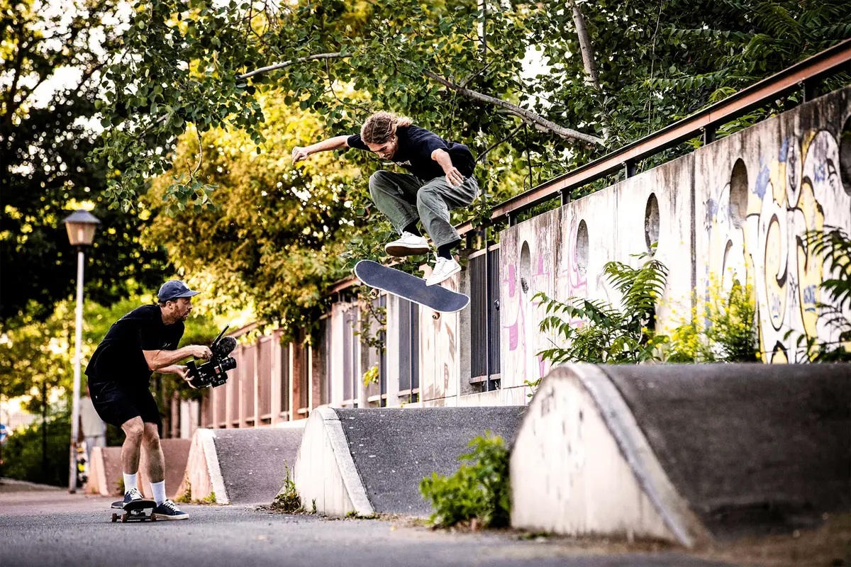 Skater mid-air over a ledge, filmer crouched below